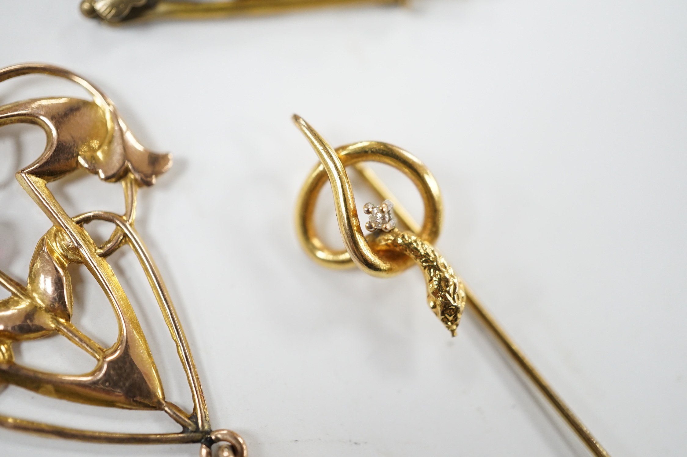 An Art Nouveau yellow metal and two stone gem set drop pendant, 53mm, an articulated Mr Punch charm and a modern 9ct gold and diamond chip set serpent stick pin.